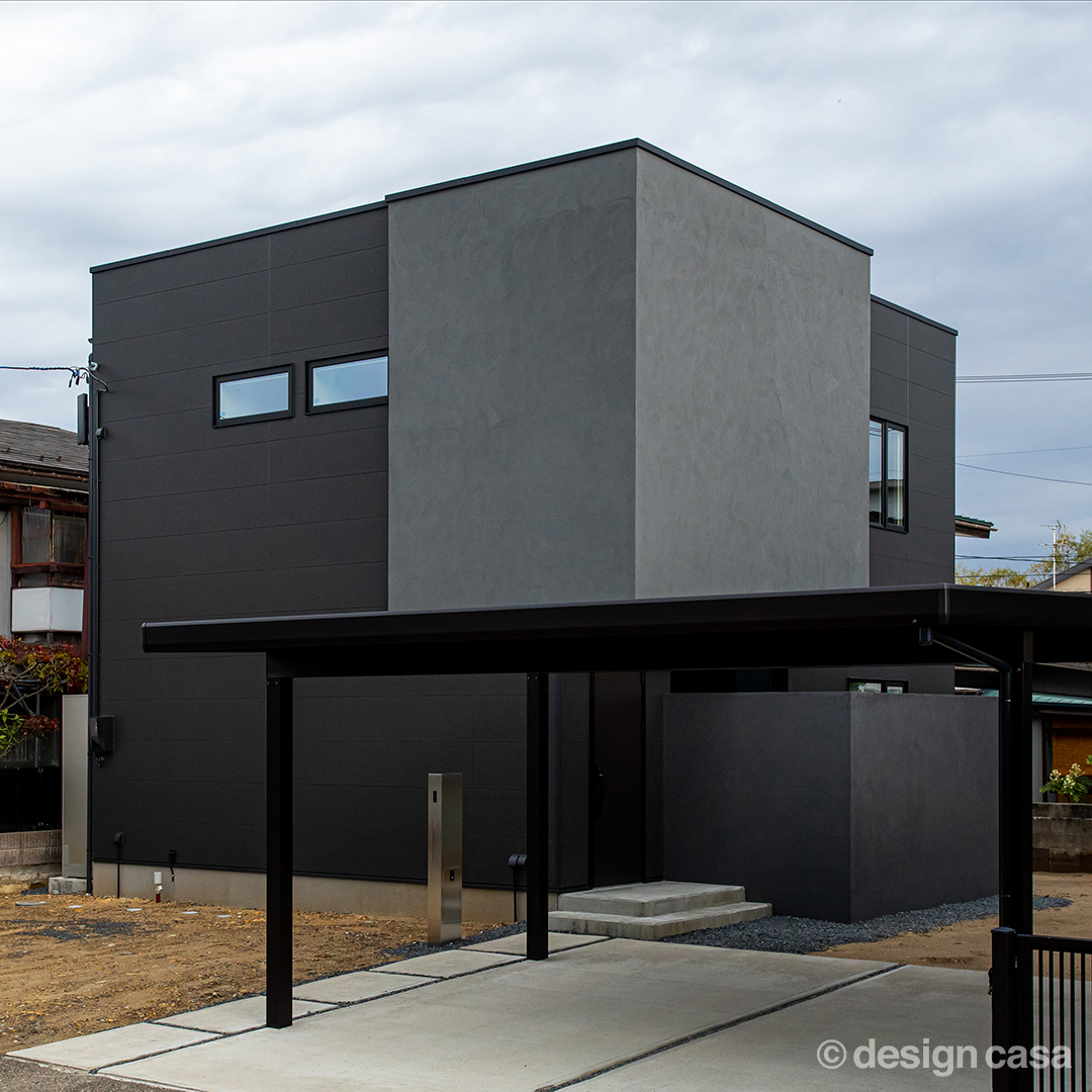 グレーの塗り壁をアクセントにモノトーンで統一されたキューブ型の家